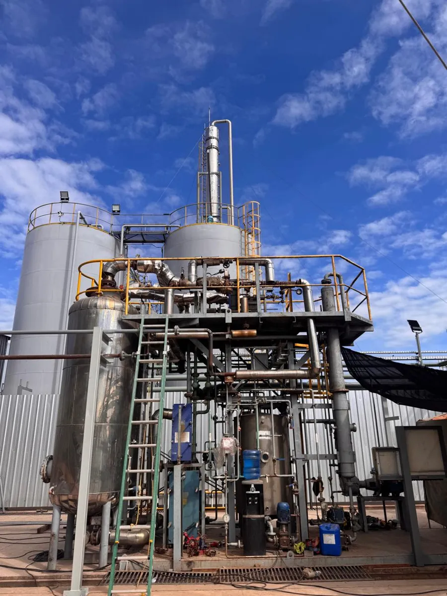 Planta industrial con tanques, columna de destilación y estructura de proceso
